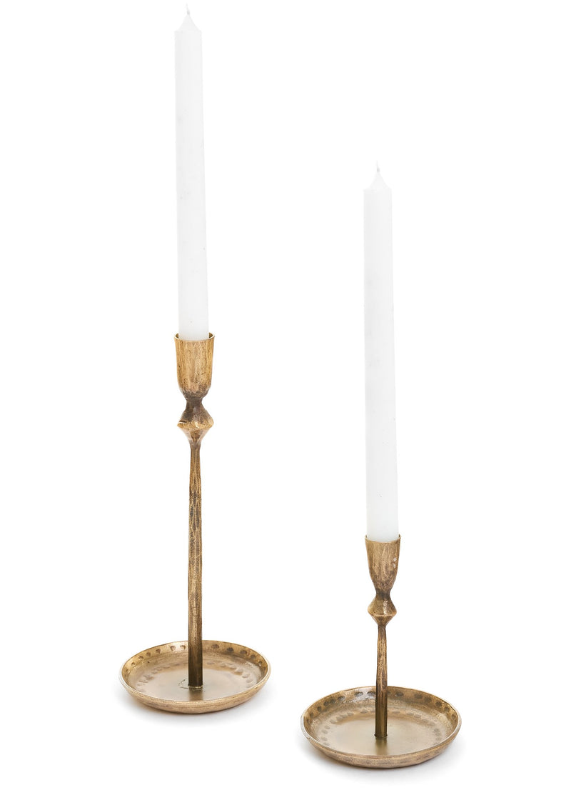 Two Small Candle Hold - Iron Antique Brass from MyHomeDecor.ca with a rustic finish are shown, each holding a tall, white taper candle. The Small Candle Hold - Iron Antique Brass have a slim, elegant design with a slightly wider base for stability. The height of the holders differs slightly, adding visual interest and highlighting their unique brass dimensions.