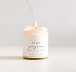 A lit white candle in a small glass jar with a minimalist white label. The label text reads "KIWI goyave," highlighting tropical and fruity scents: “agave | ananas | lime” and “par Marée Chandellettes” below it. The background is soft and out of focus, emphasizing the environmentally friendly Large Soy Candle - Kiwi & Guava by MyHomeDecor.ca.