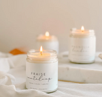 Three lit Large Soy Candle - Strawberry & Cantaloupe by MyHomeDecor.ca in glass jars are placed on a white fabric-draped surface. The jars have minimalist labels, with text on the foreground candle reading "FRAISE cantaloup." The scene is softly lit, evoking a calm and cozy ambiance, and emphasizes an environmentally friendly touch.