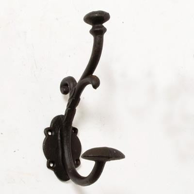 The Roddy Wall Hook - Black by MyHomeDecor.ca, crafted from black wrought iron, features a decorative curved design with two hooks—one smaller on top and one larger below. Its scalloped-edged wall mount stands out beautifully against a plain white background.