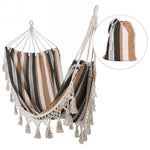 A MyHomeDecor.ca Hanging Hammock With Pouch - Black, White and Ocher hangs on display. The chair features decorative fringe tassels along the bottom hem. Inset shows a matching storage bag with the same striped pattern and a drawstring closure—an ideal gift idea for a farmhouse-style porch.