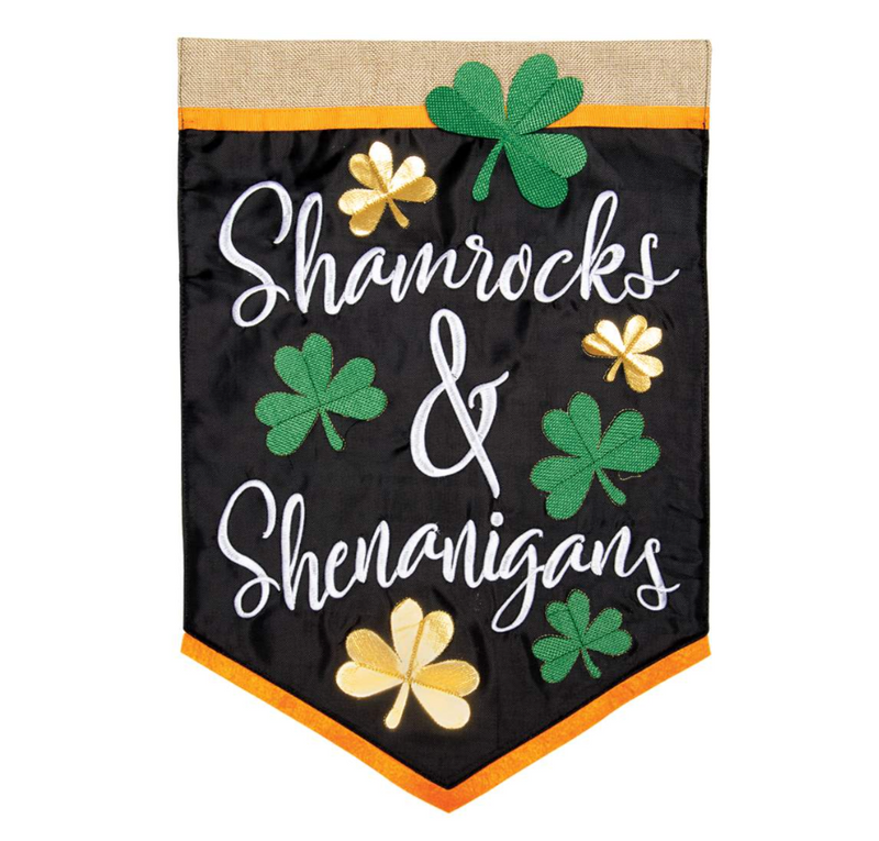 A long black flag - App Shenanigans by MyHomeDecor.ca featuring the words "Shamrocks & Shenanigans" in elegant white script. Adorned with green and gold shamrocks, it also has a burlap section at the top and an orange trim at the bottom, perfect for your Spring-Summer decor.